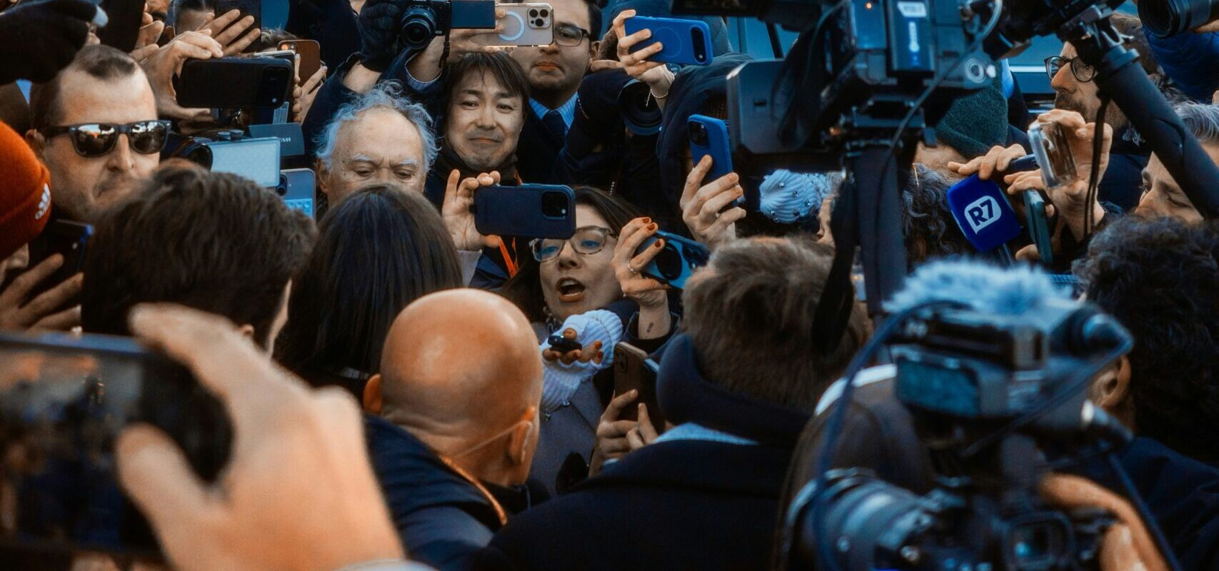Eine Menge Fotografen drängt sich vor einem politischen Gebäude.