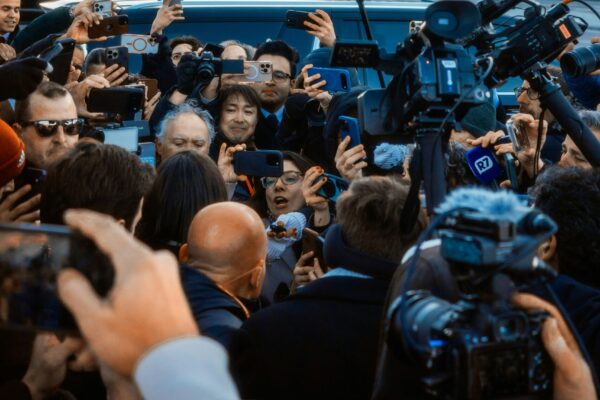 Eine Menge Fotografen drängt sich vor einem politischen Gebäude.